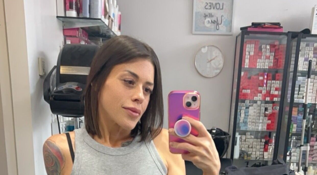 Client at Sheena McCart, Vancouver, BC, CA, takes a salon selfie in front of hair products.