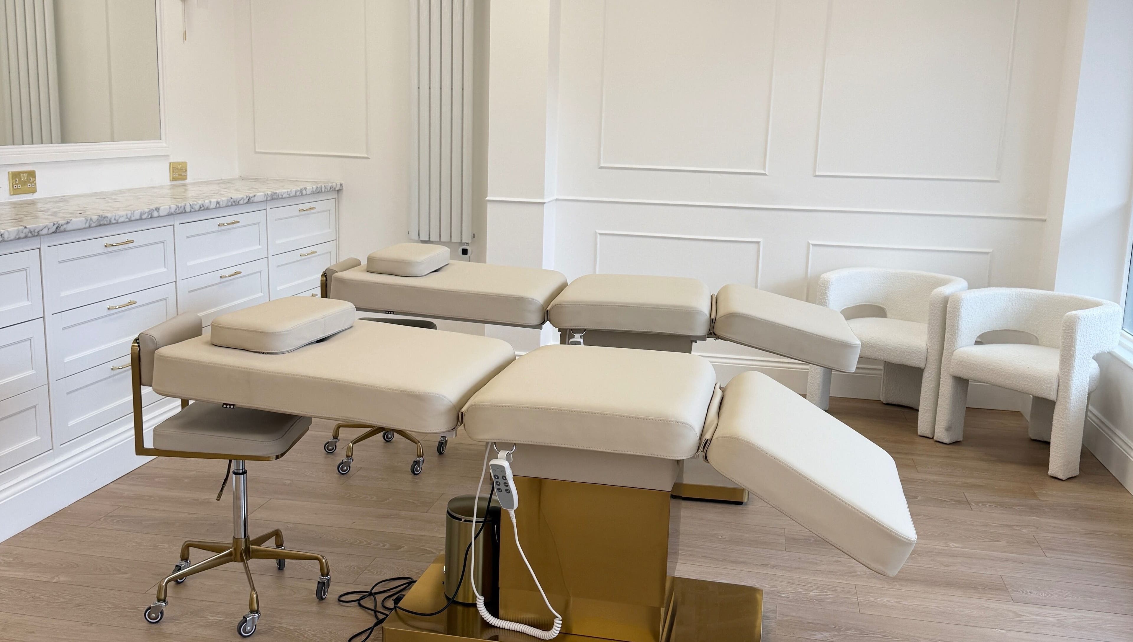 Luxurious treatment room at Studio 22 in Ripley, England, GB with modern beige chairs and sleek counters.