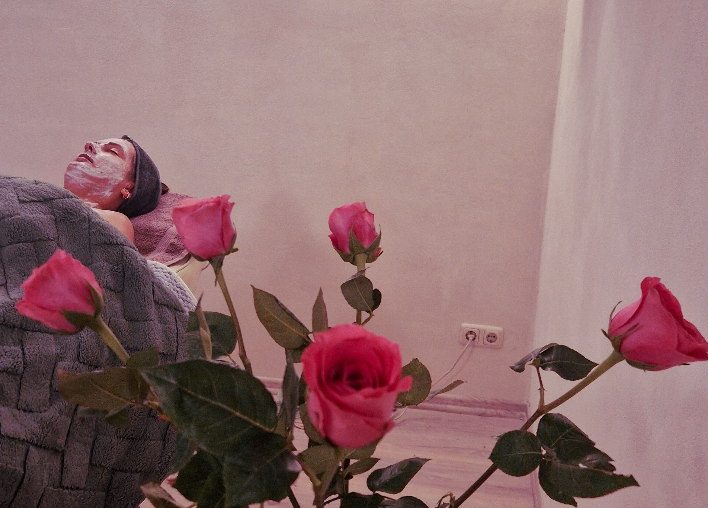 Relaxing facial treatment at Ķermeņa procedūras Pārdaugavā in Rīga, LV with pink roses enhancing ambiance.