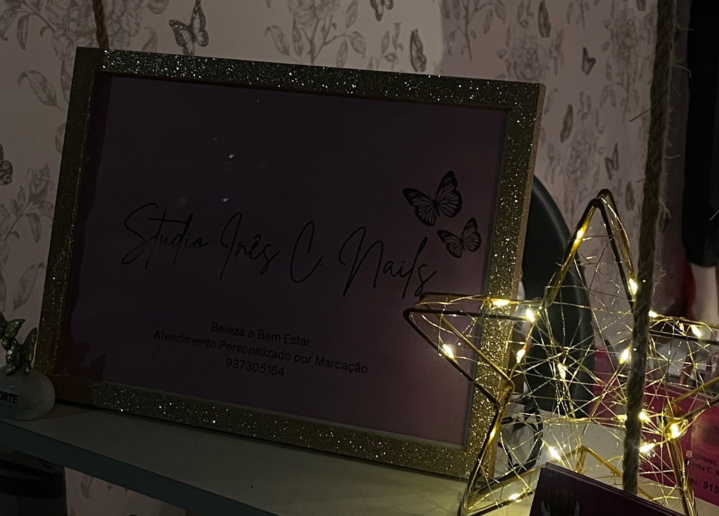Decoração luminosa no Studio Inês C. Nails, Baixa Da Banheira, PT, com moldura dourada e borboletas.