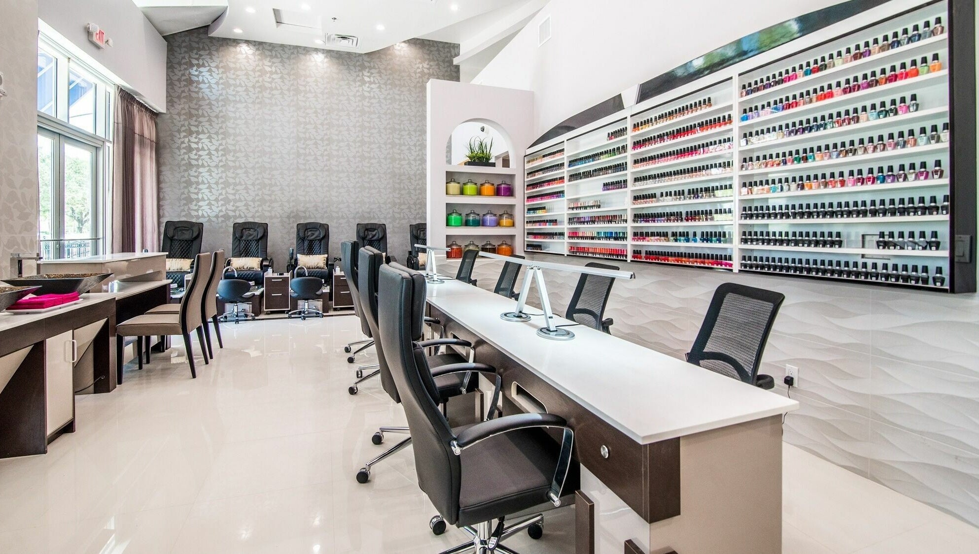 Elegant interior of Glow Spa and Nails in Houston, Texas, US; showcases modern chairs and vast nail polish selection.