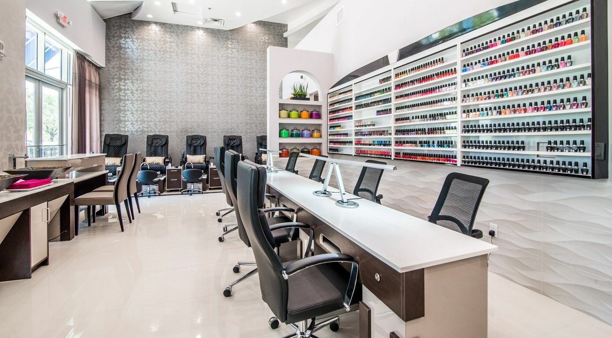 Elegant interior of Glow Spa and Nails in Houston, Texas, US; showcases modern chairs and vast nail polish selection.