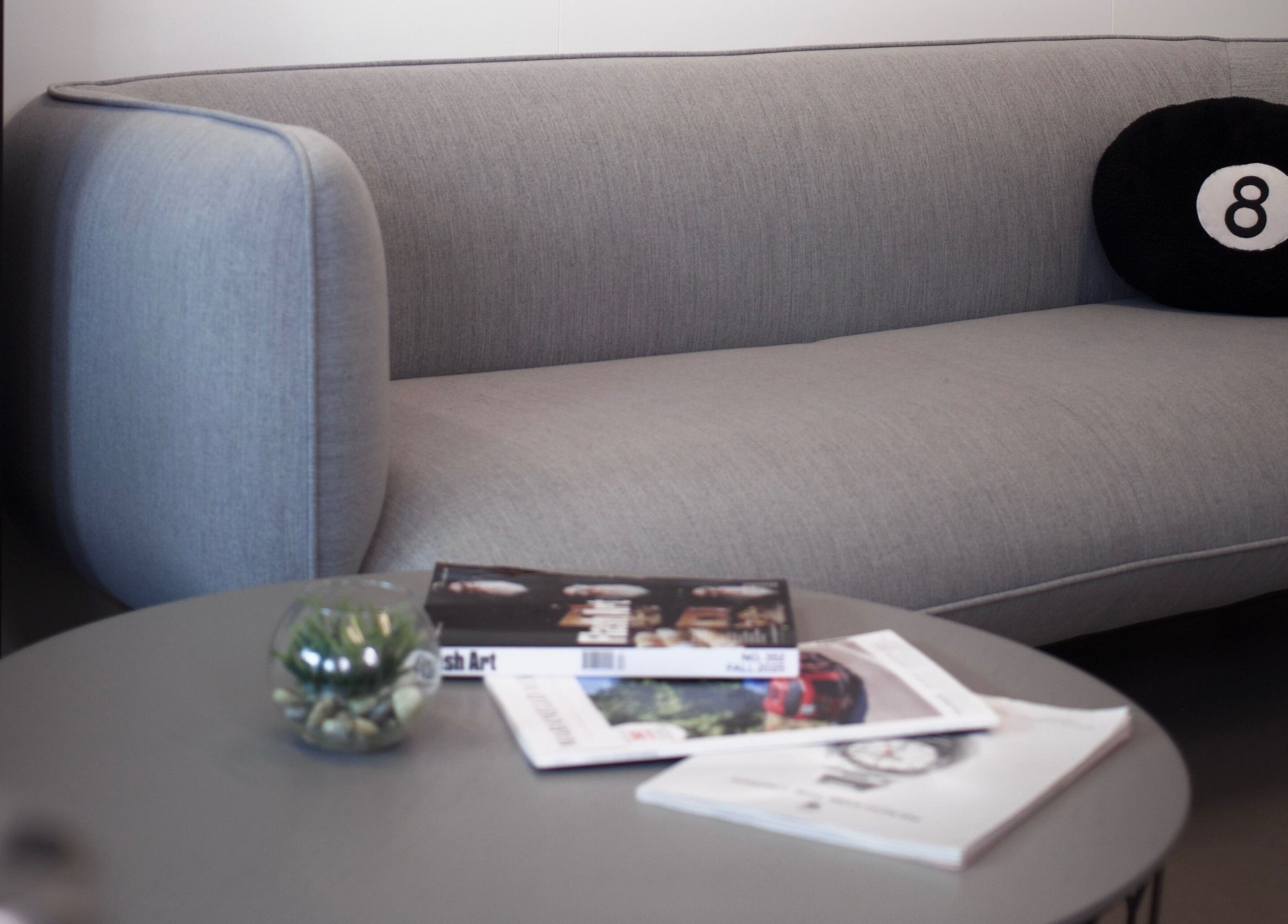 Moderne grijze bank en tafeltje in wachtkamer bij Ferra Cuts, Rotterdam, Zuid-Holland, NL.