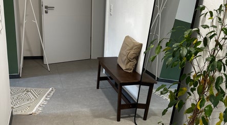 Wartebereich bei jb.massage in Zetel, Niedersachsen, DE mit Bank, Spiegel und Pflanzen.