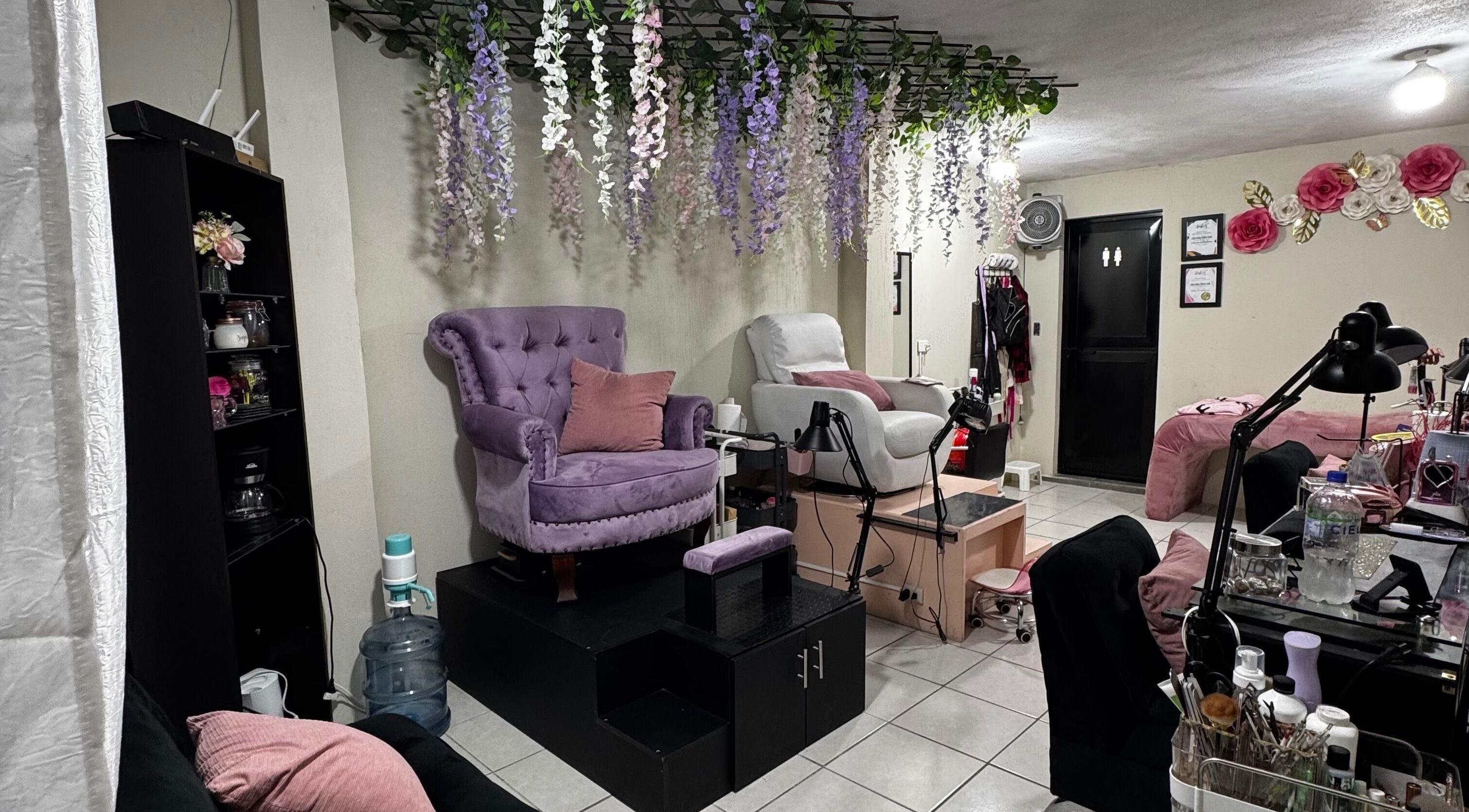 Interior de Nails Studio en Ciudad De Guatemala, Guatemala, GT, con sillas elegantes y decoración floral.