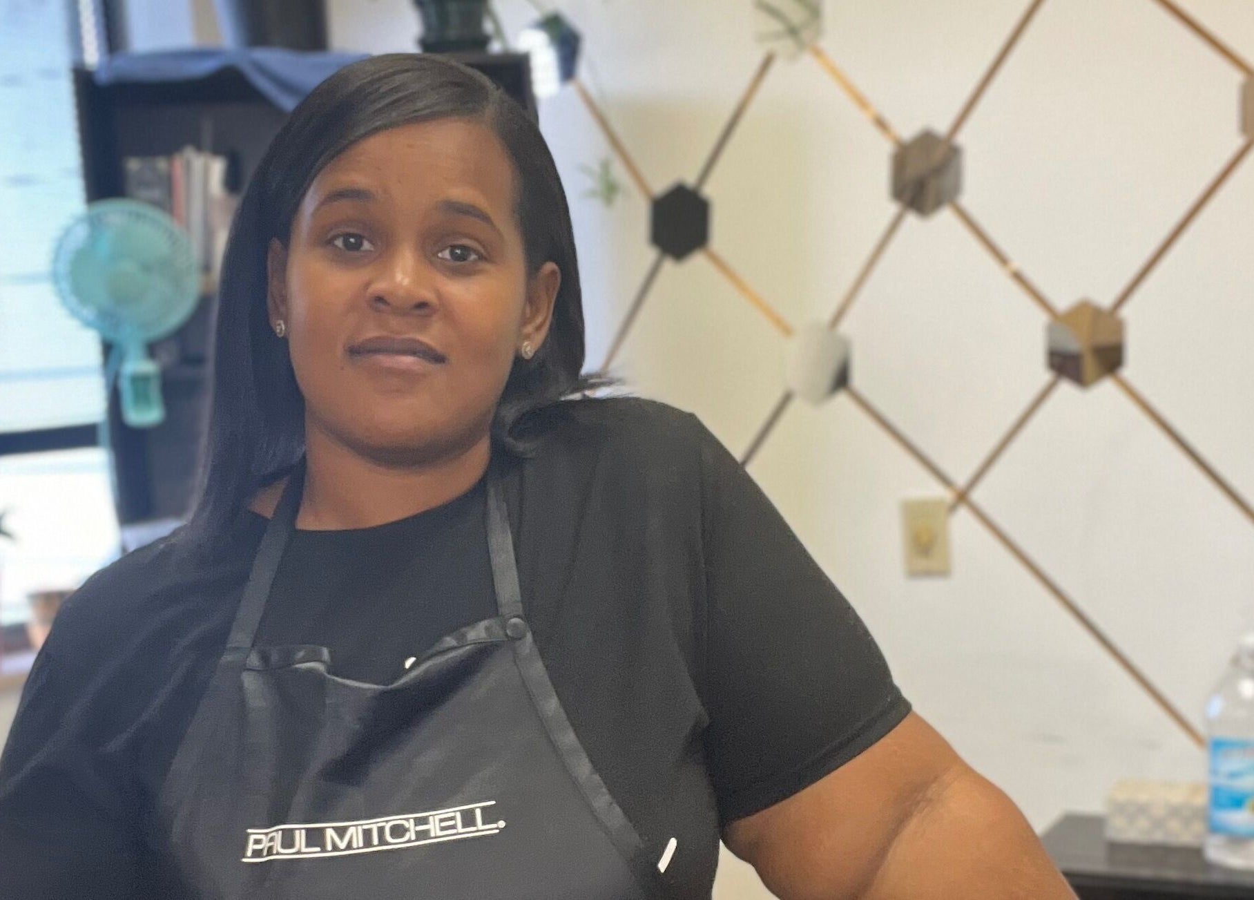 Stylist at Tasja’s Style Studio in Madison, Wisconsin, US with hexagonal wall decor and modern setup.