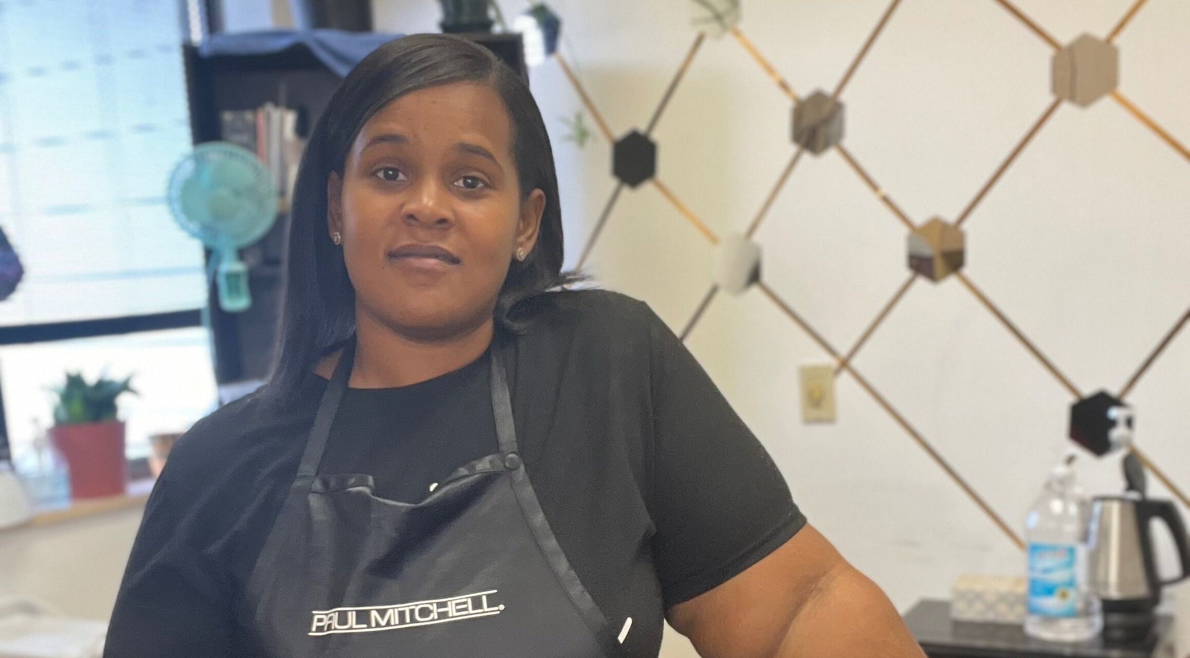 Stylist at Tasja’s Style Studio in Madison, Wisconsin, US with hexagonal wall decor and modern setup.