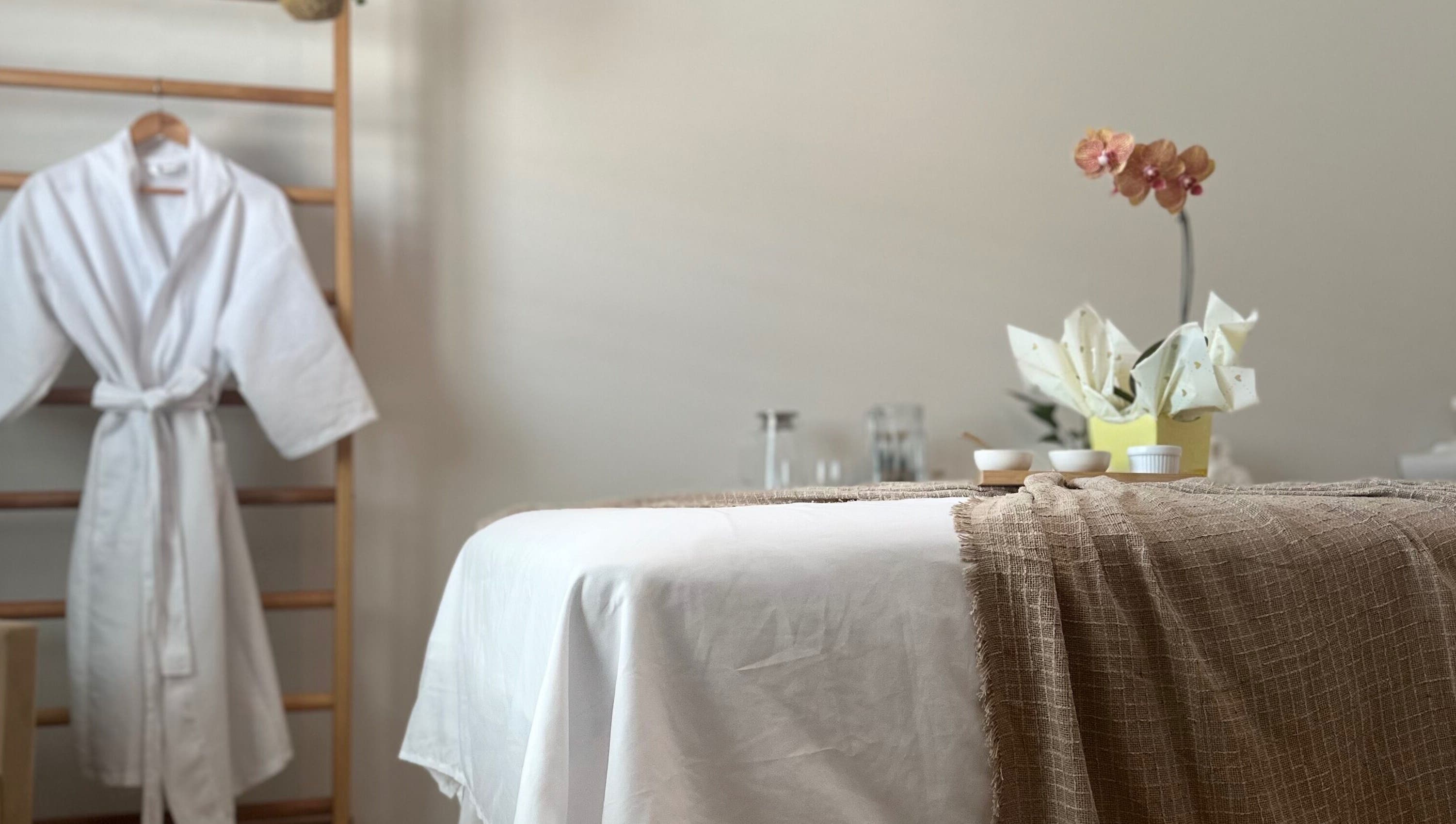 Ambiente de relaxamento com mesa de massagem e roupão em Terapias de SPA - Heloisy Coleta, São Paulo, BR.