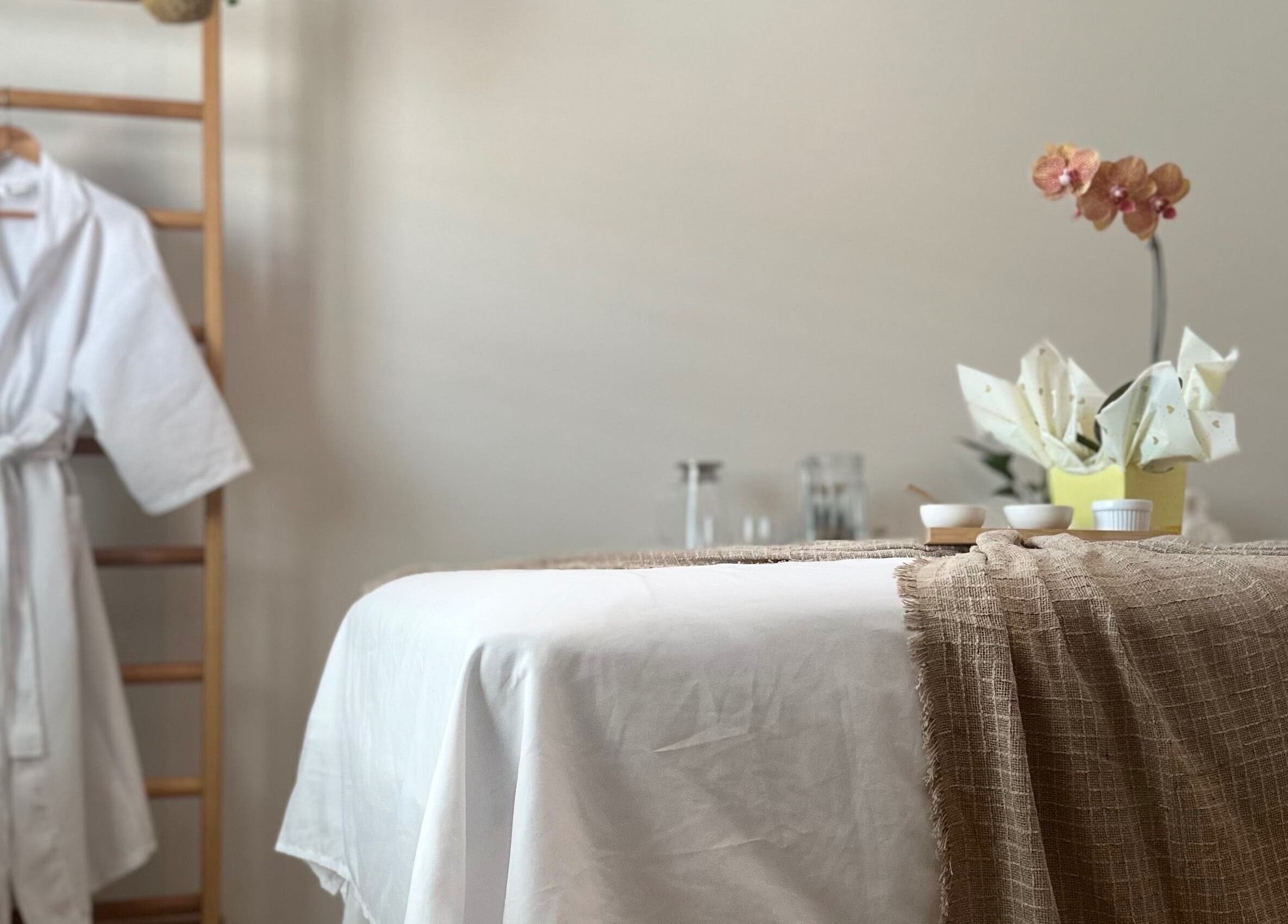 Ambiente de relaxamento com mesa de massagem e roupão em Terapias de SPA - Heloisy Coleta, São Paulo, BR.