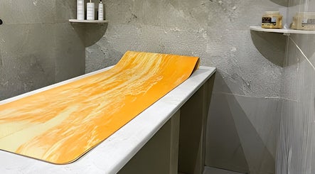 Relaxing treatment room at Ambra Beauty, Abu Dhabi, AE, featuring a soothing massage table with orange accents.