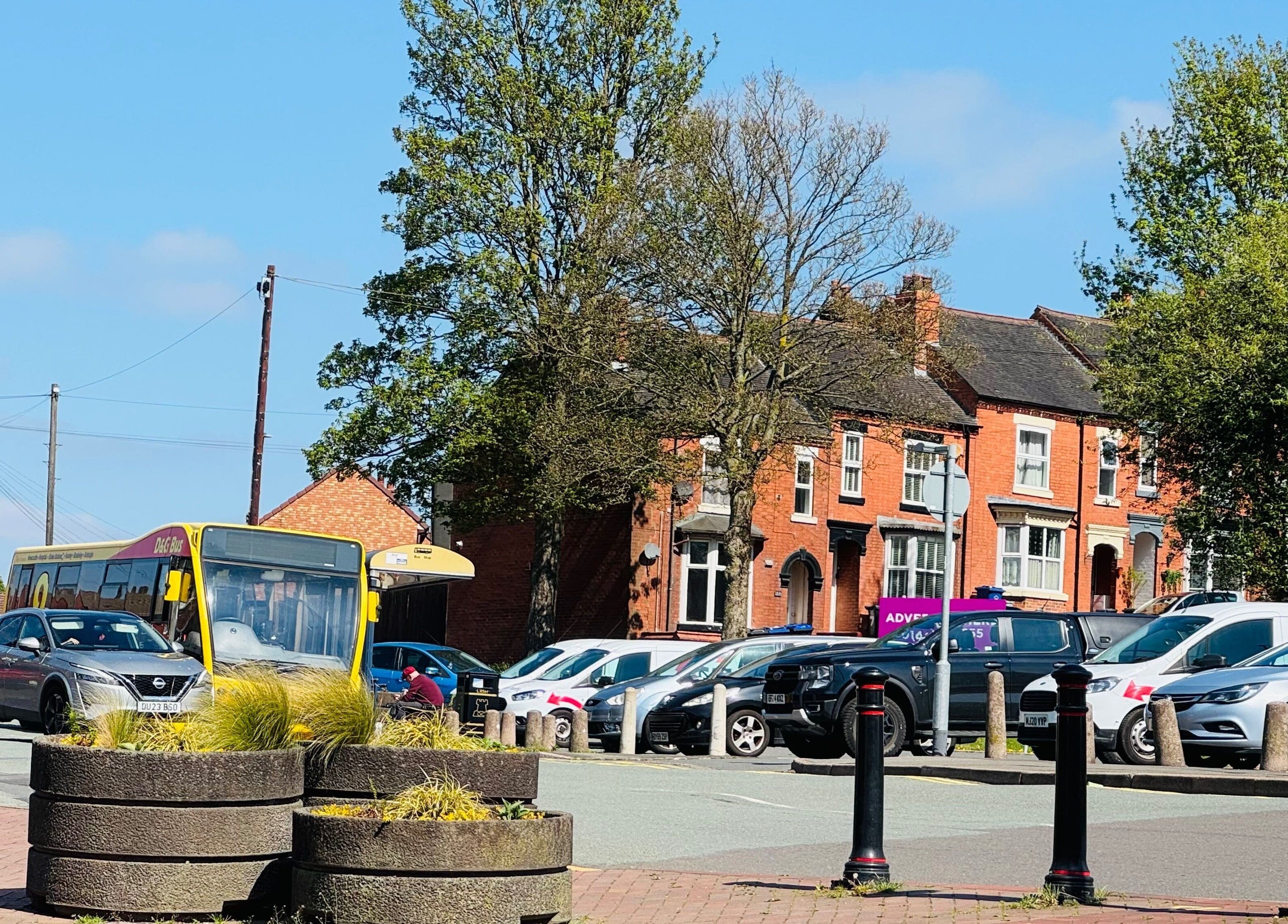 Street view near Cloud 9 Wellness Spa & Rooms in Newcastle Under Lyme, England, featuring parked cars and old brick buildings.