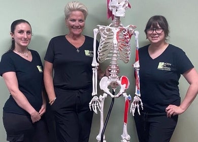 Instructors at Body in Mind Massage Institute - Toms River, NJ, pose with a skeleton model.