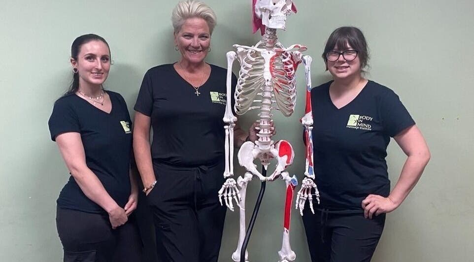 Instructors at Body in Mind Massage Institute - Toms River, NJ, pose with a skeleton model.