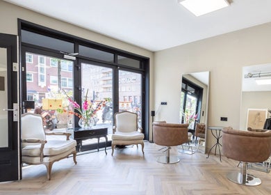 Elegant interieur van Salon Zuid in Amsterdam, Noord-Holland, NL met moderne stoelen en grote spiegels.