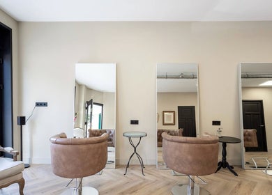 Moderne saloninrichting bij Salon Zuid in Amsterdam, Noord-Holland, NL met stijlvolle stoelen en spiegels.