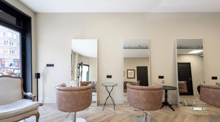 Moderne saloninrichting bij Salon Zuid in Amsterdam, Noord-Holland, NL met stijlvolle stoelen en spiegels.