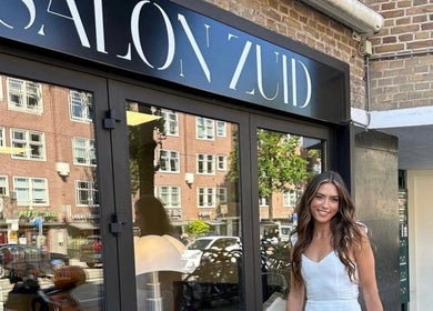 Vrouw voor Salon Zuid in Amsterdam, Noord-Holland, NL met moderne gevel en stadse achtergrond.