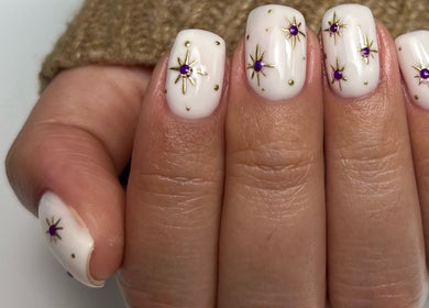Elegant starry nail art design at The Nail Place, Coachford, County Cork, IE with purple gems on white nails.