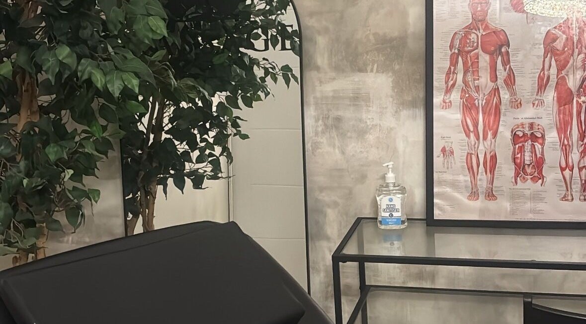 Relaxing treatment room at By Ellie Aesthetics, Liverpool, England, GB featuring anatomy poster and greenery.