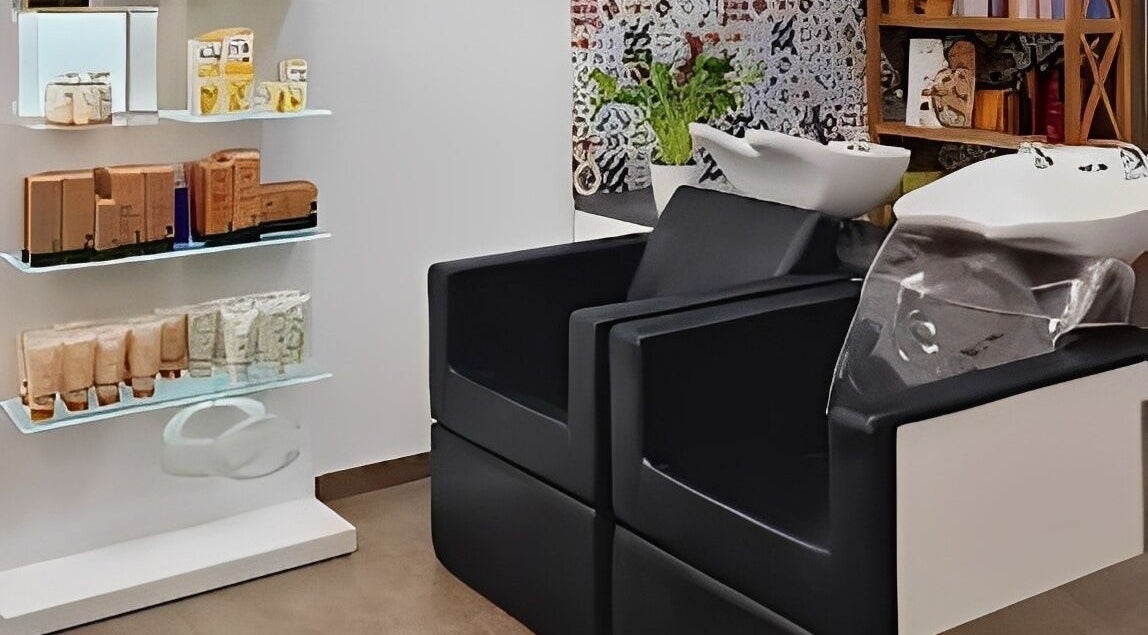 Zona de lavado en Magic Peluqueros, Sant Joan D'alacant, Comunidad Valenciana, ES, con sillas y productos de belleza.