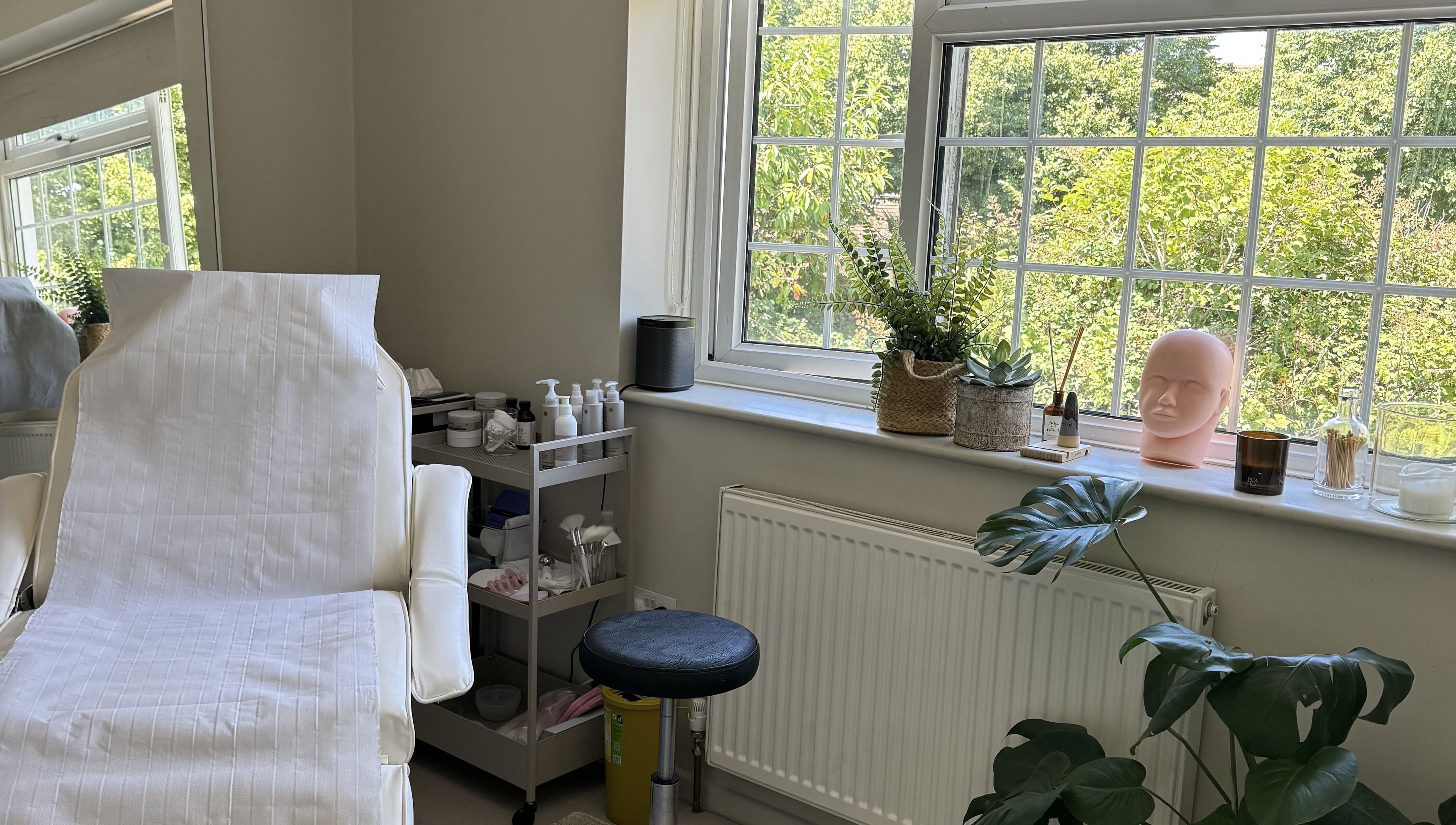 Relaxing treatment room at Solara Studio, Christchurch, GB, with a serene view through large windows.