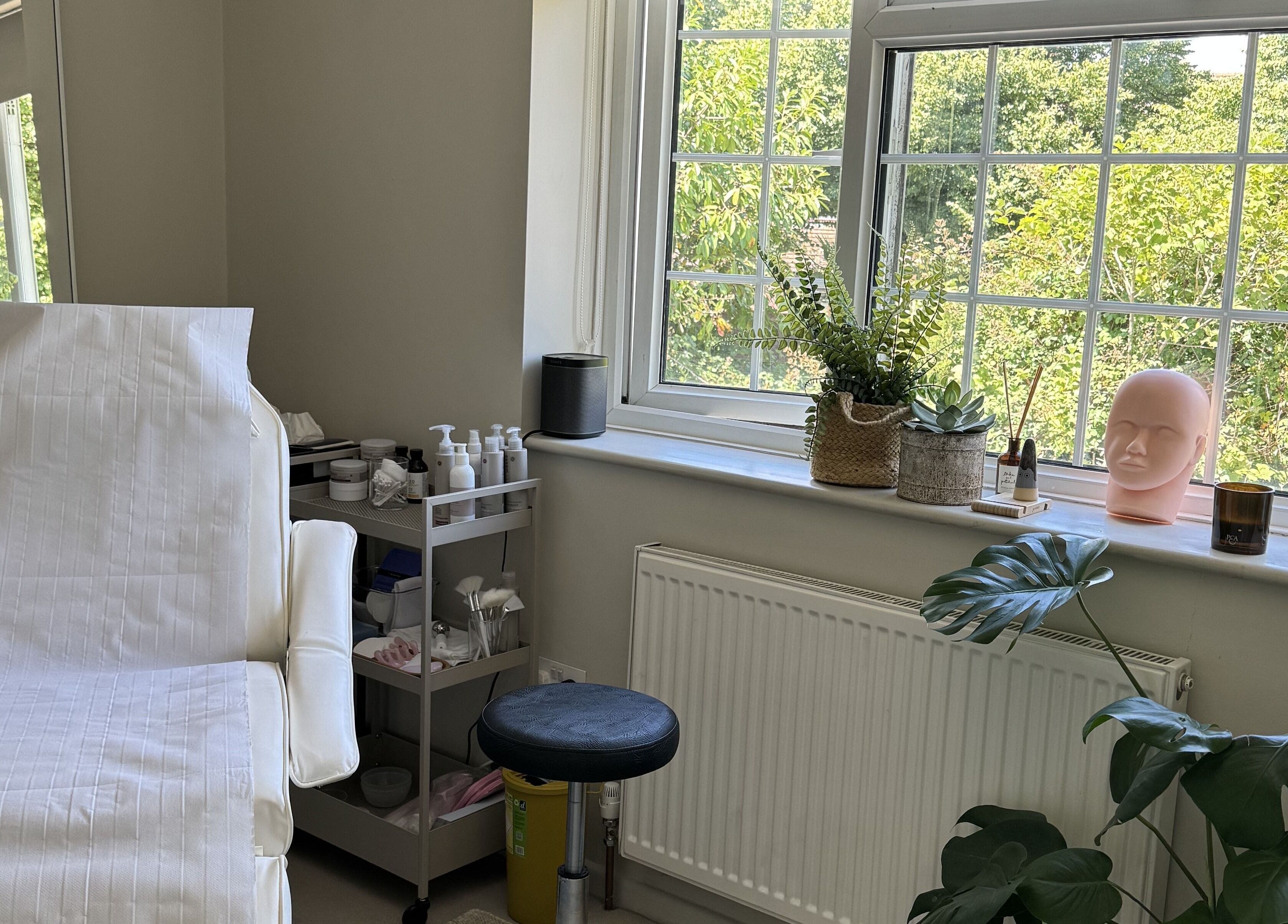 Relaxing treatment room at Solara Studio, Christchurch, GB, with a serene view through large windows.