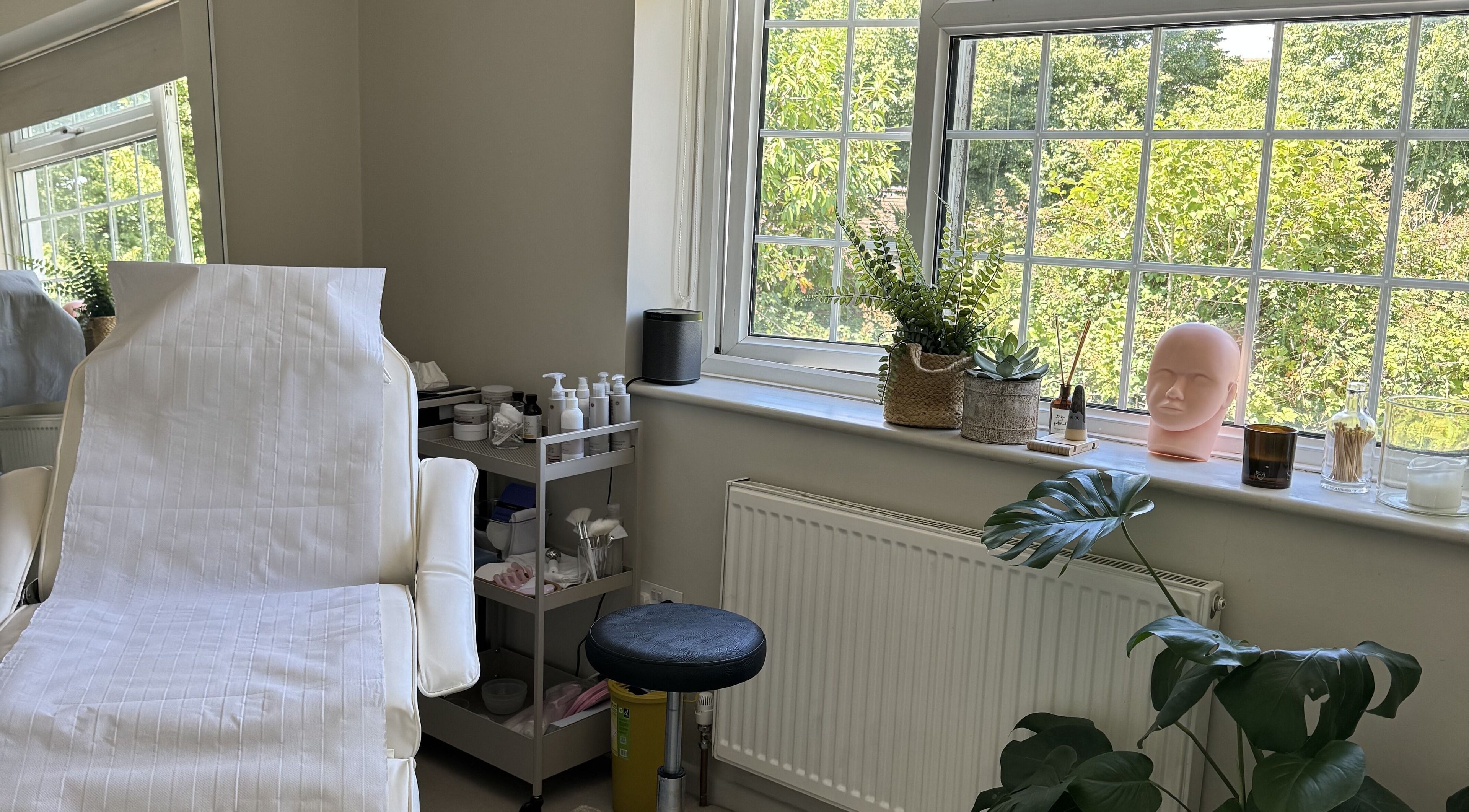 Relaxing treatment room at Solara Studio, Christchurch, GB, with a serene view through large windows.