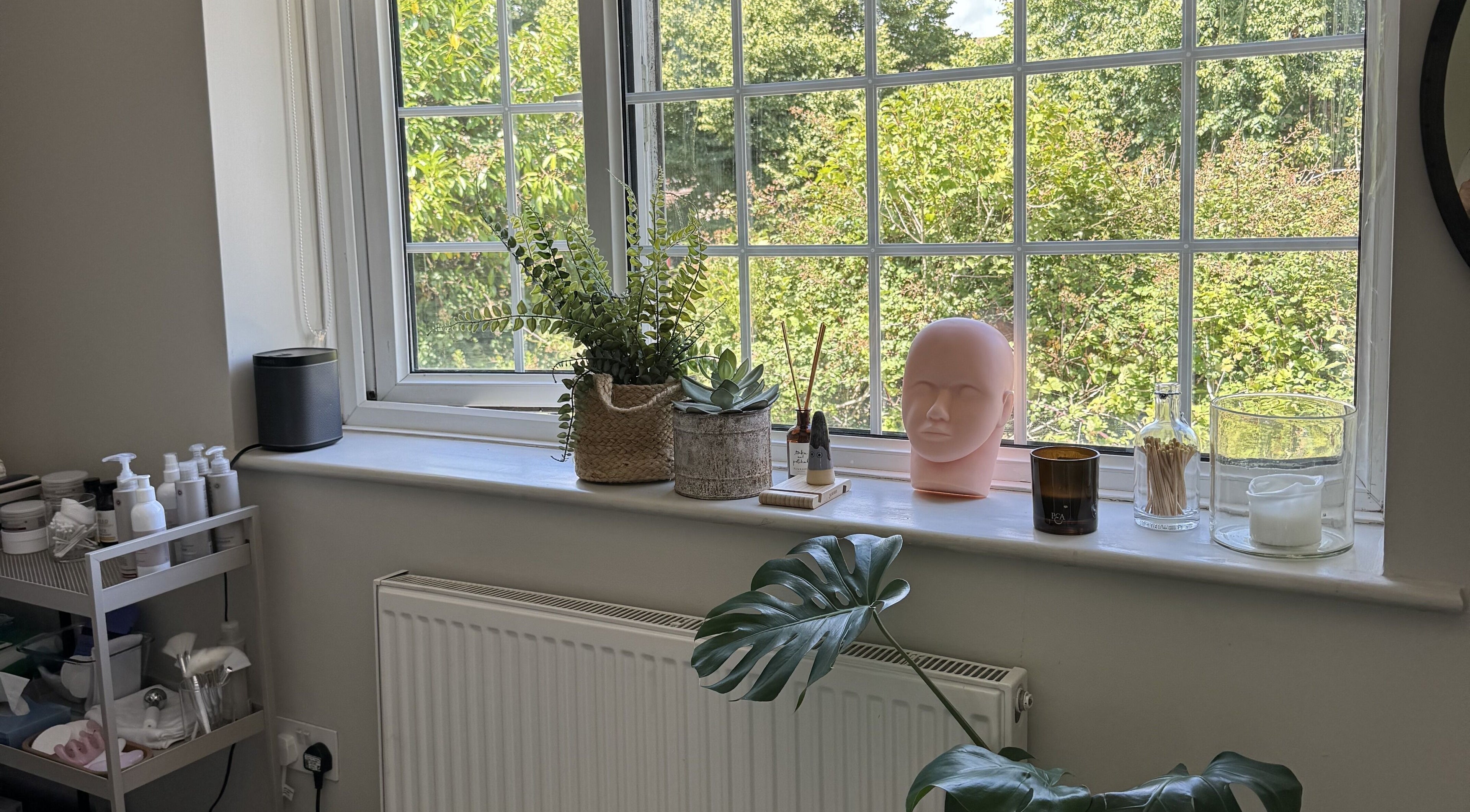 A calming window display with plants and candles at Solara Studio, Christchurch, GB.