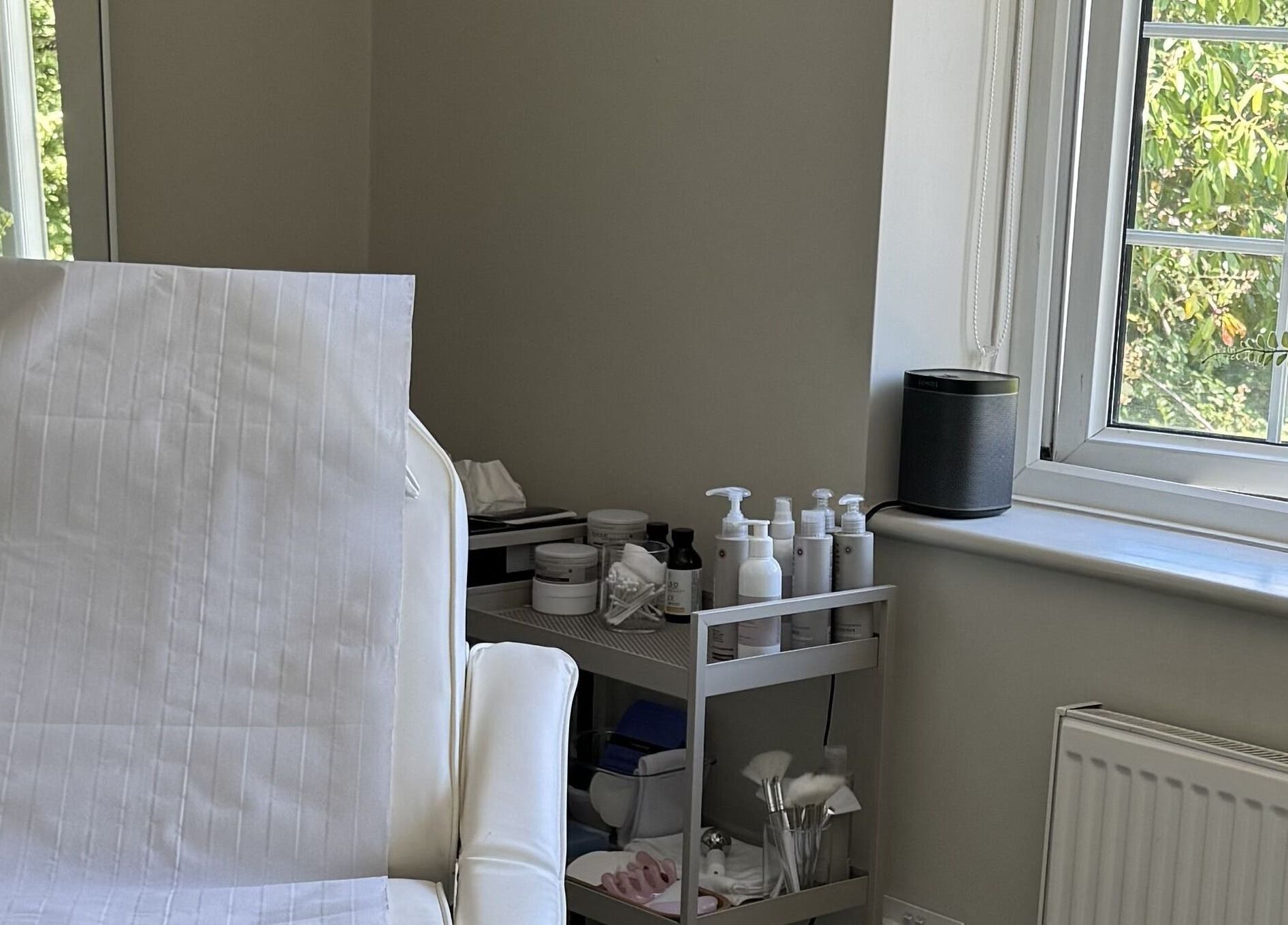 Bright treatment room at Solara Studio, Christchurch, GB, featuring a spa bed and skincare products.