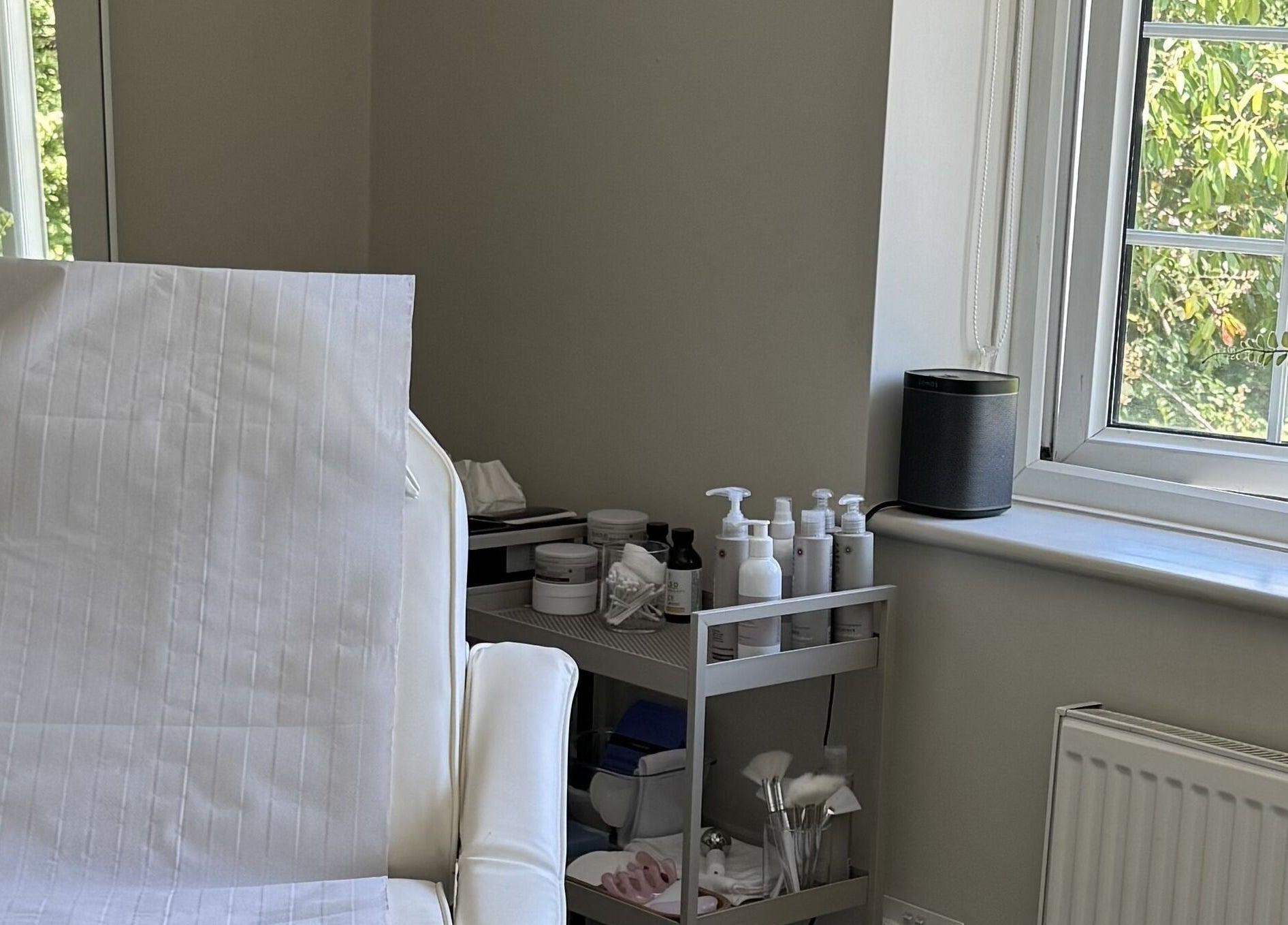Bright treatment room at Solara Studio, Christchurch, GB, featuring a spa bed and skincare products.