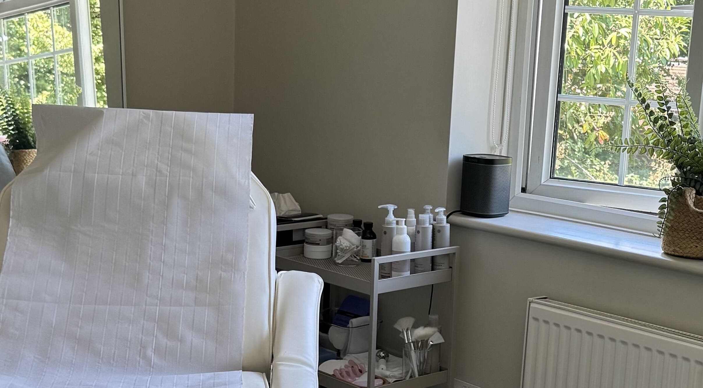 Bright treatment room at Solara Studio, Christchurch, GB, featuring a spa bed and skincare products.