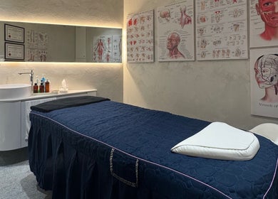 Treatment room at The Rehabist, Singapore, SG with a stylish massage bed and anatomical art.