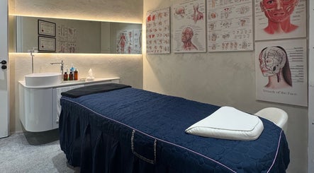 Treatment room at The Rehabist, Singapore, SG with a stylish massage bed and anatomical art.