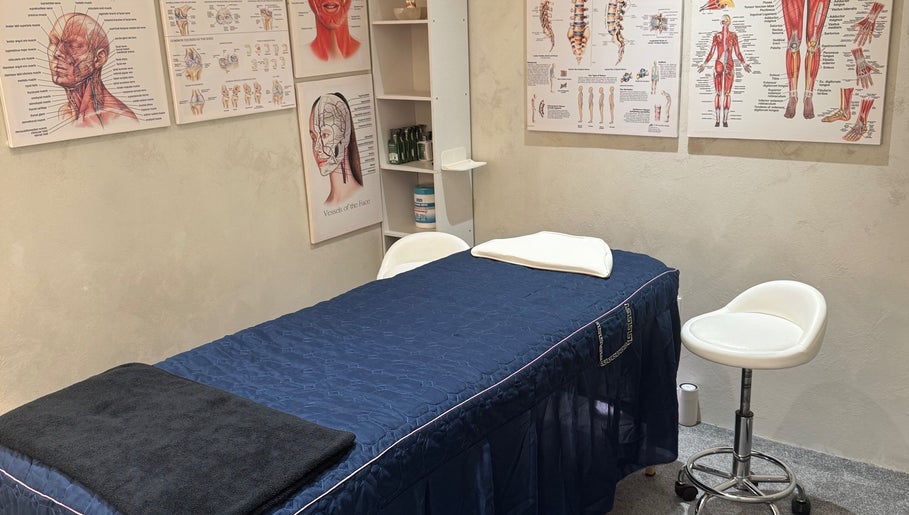Massage therapy room at The Rehabist, Singapore, SG featuring anatomical charts and a treatment table.