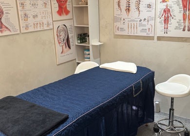 Massage therapy room at The Rehabist, Singapore, SG featuring anatomical charts and a treatment table.