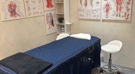 Massage therapy room at The Rehabist, Singapore, SG featuring anatomical charts and a treatment table.