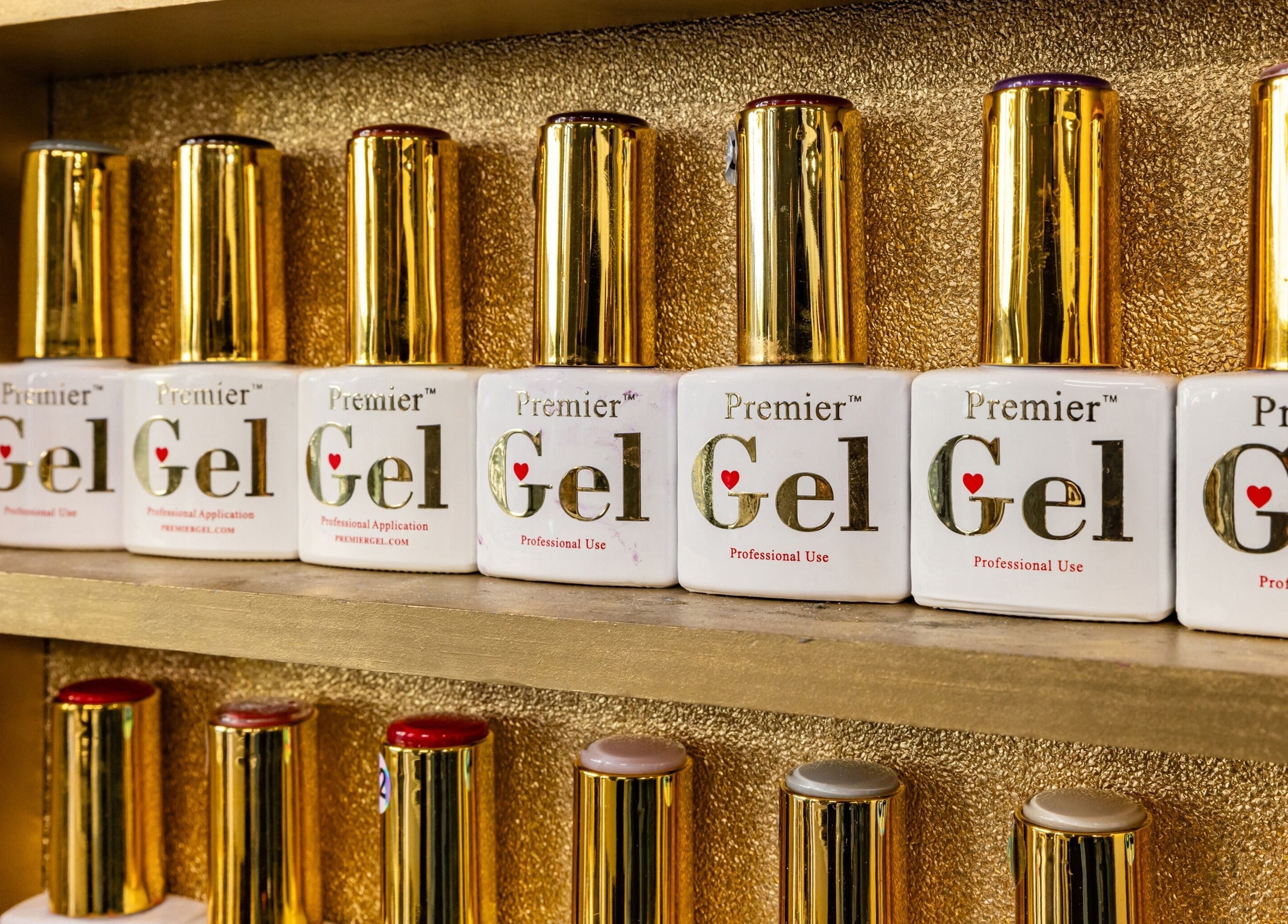Premier Gel polish bottles on display at Dima Beautiful in London, England, GB. Luxurious golden backdrop.