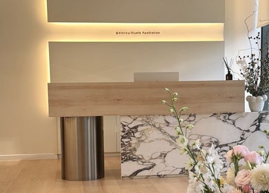 Reception area at Skyns Aesthetics Clinic in Nicosia, Nicosia, CY, featuring a modern marble desk and floral decor.