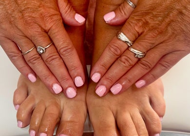 Close-up of manicured hands and feet with pink polish at Pixie Glow Aesthetics, Harlow, England, GB.