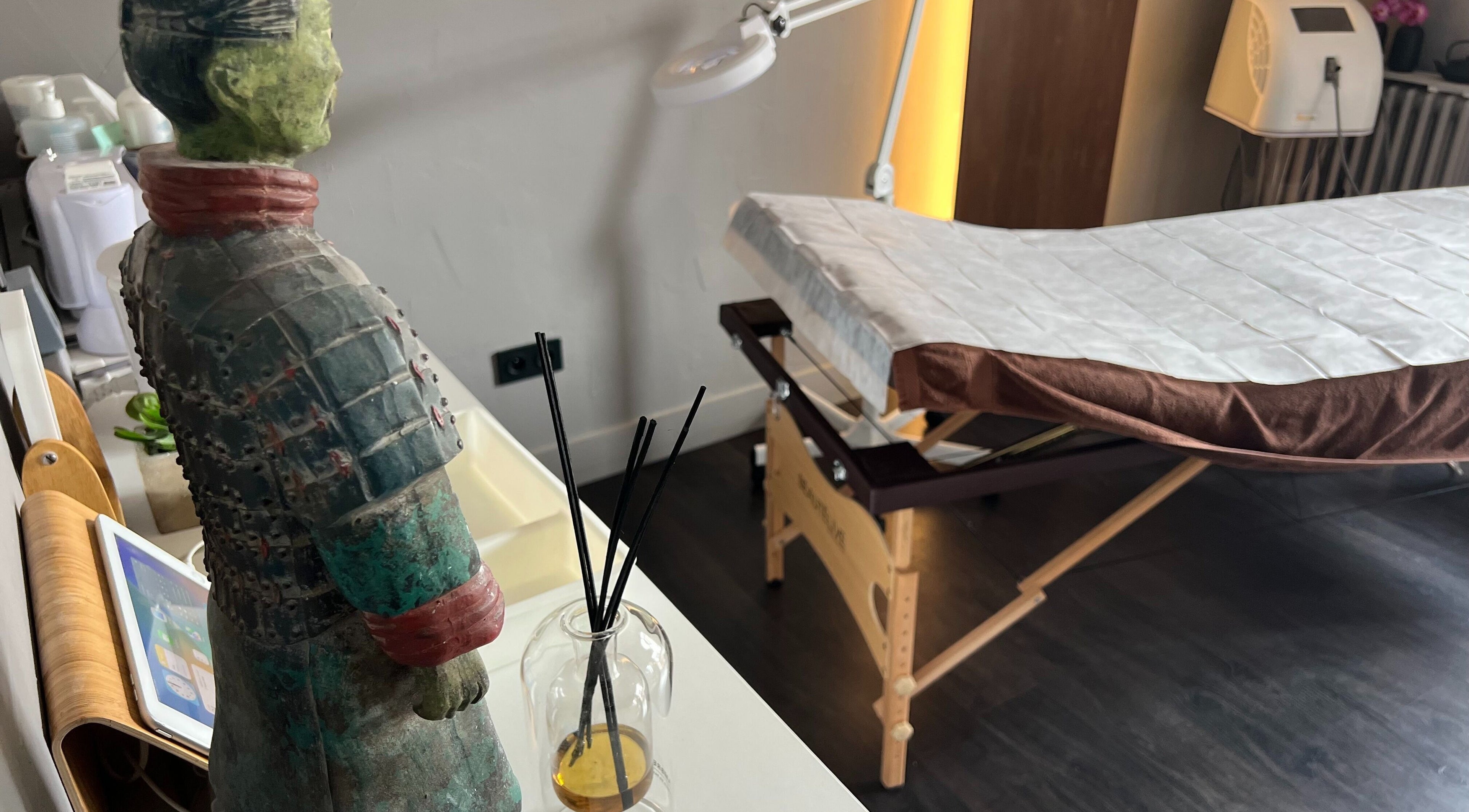 Salle de soin chez Epilation pour Hommes 34 à Montpellier, Occitanie, FR avec table de massage et statue zen.