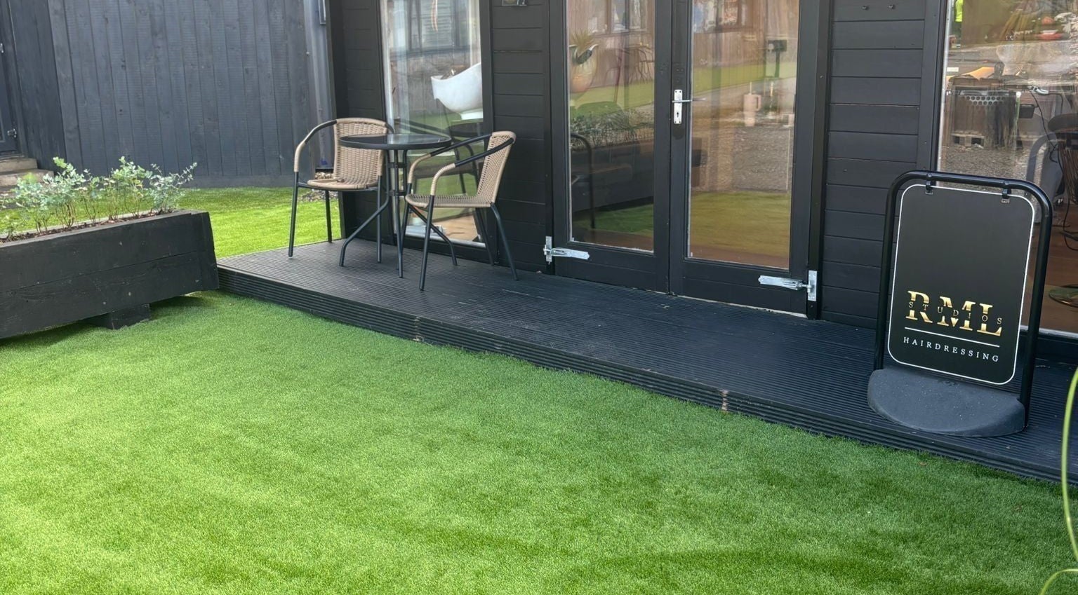 Outdoor seating and RML Studios sign at Brentwood, England, GB, on a lush green lawn.