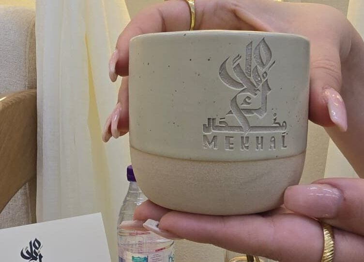 Elegant hands holding a branded cup from صالون مكحال in Riyadh, Riyadh Province, SA.