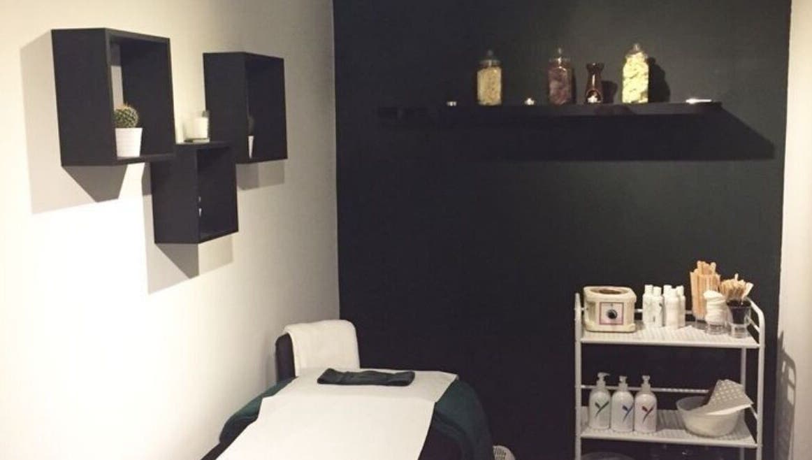 Treatment room at The Lash Alchemist in Montego Bay, St. James Parish, JM with a bed and shelves.