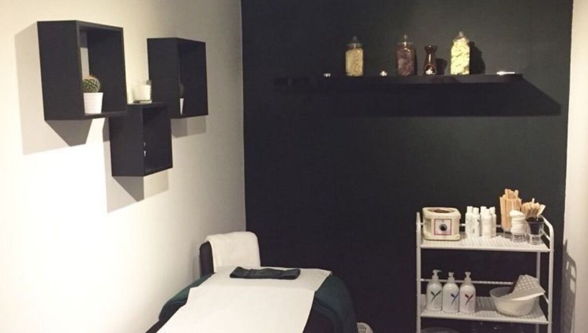 Treatment room at The Lash Alchemist in Montego Bay, St. James Parish, JM with a bed and shelves.