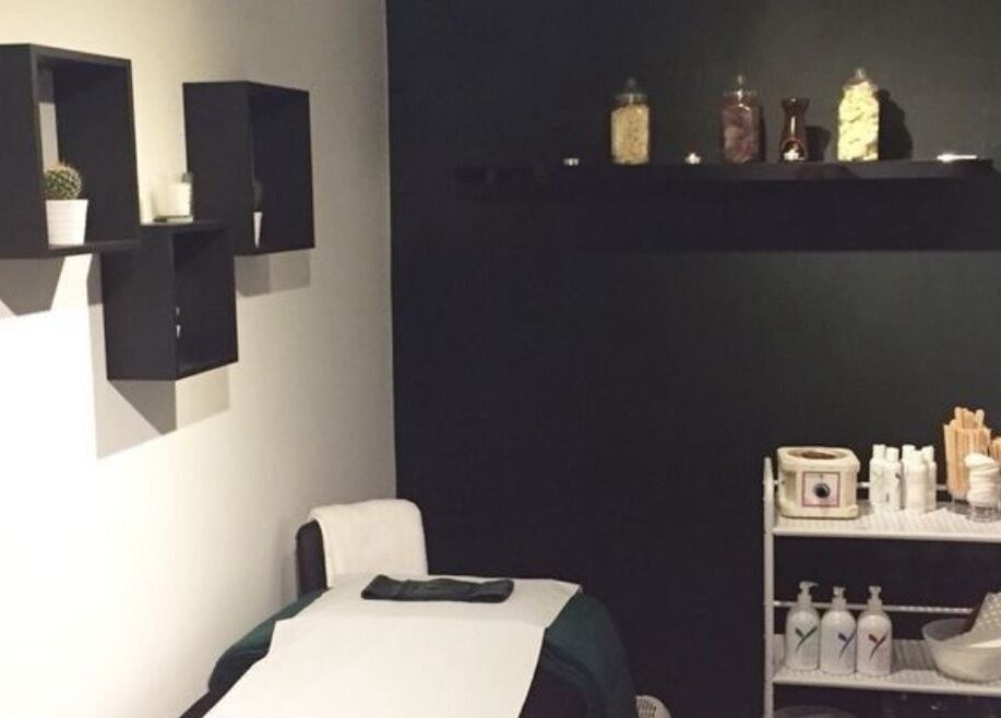 Treatment room at The Lash Alchemist in Montego Bay, St. James Parish, JM with a bed and shelves.