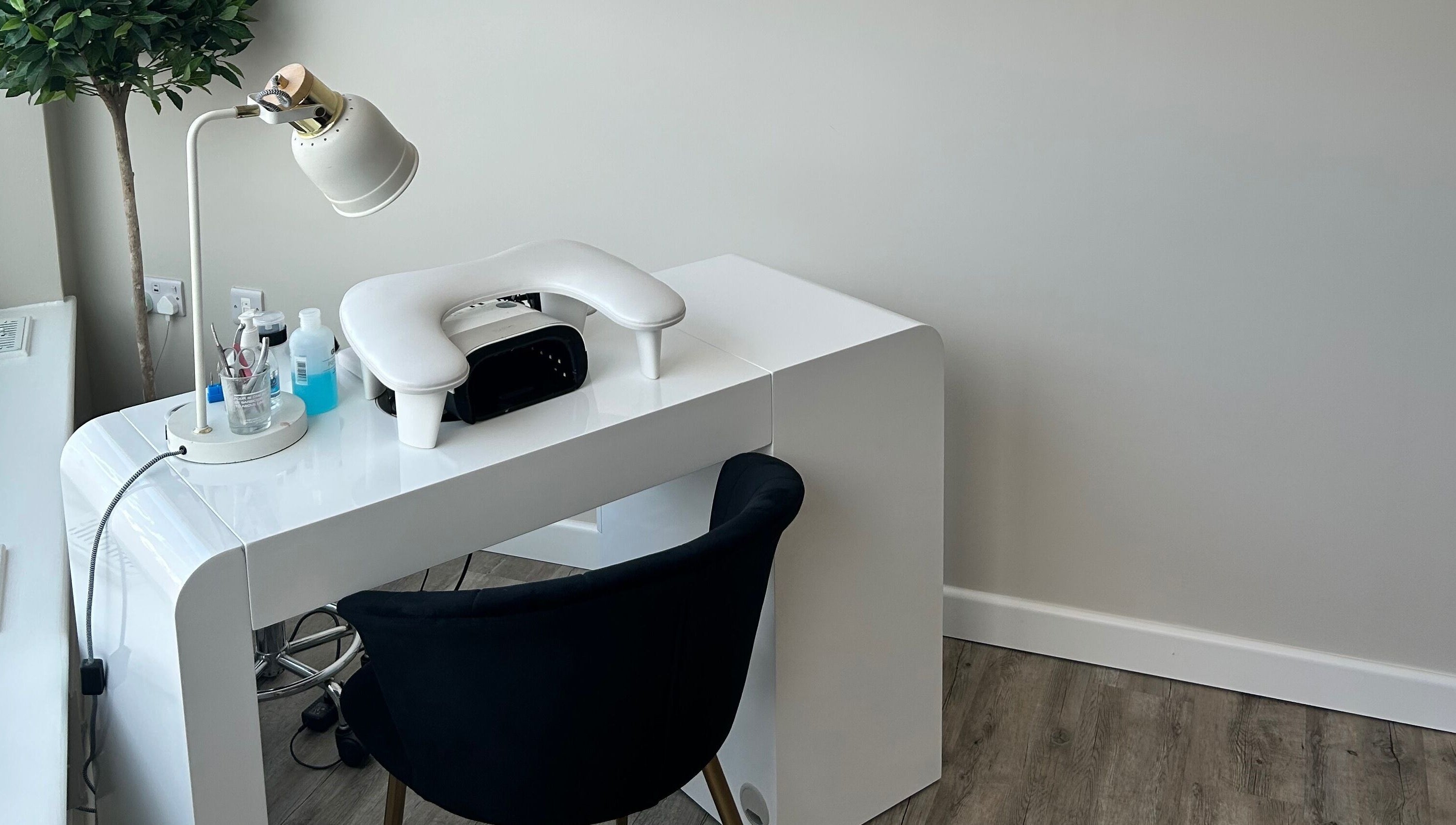 Modern nail station at Megan’s Beauty, Norwich, England, GB with white desk and plush chair.