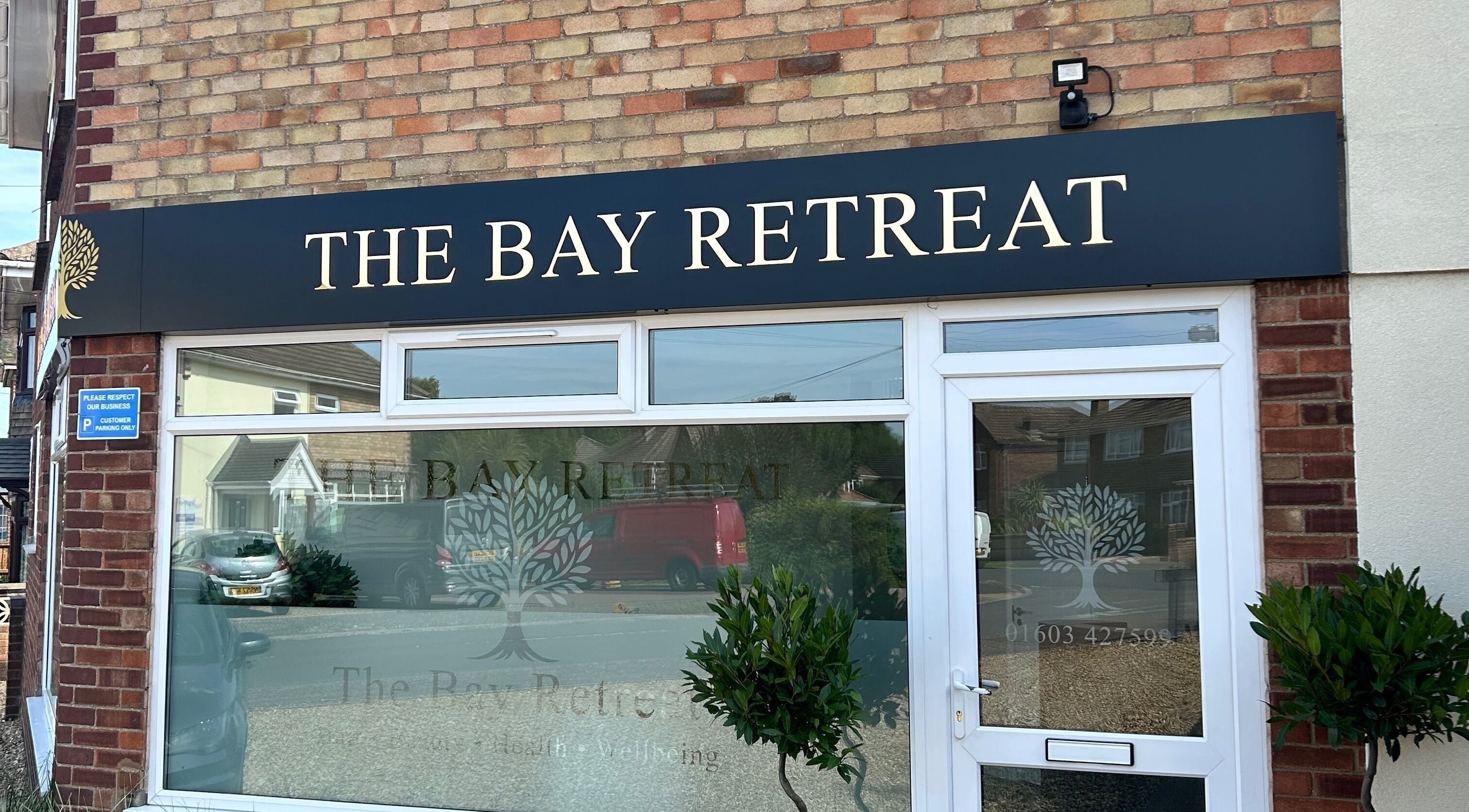 Front of Megan’s Beauty in Norwich, England, GB with elegant signage and potted plants.