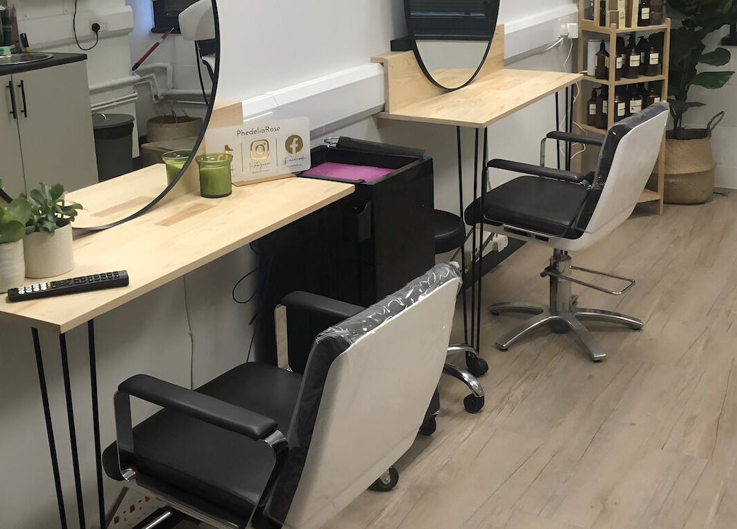 Modern salon chairs at PhedeliaRose, London, England, GB, with mirrors and plants on wooden desks.