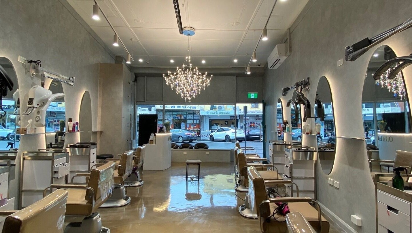 Interior of Ora No1 beauty salon in Lidcombe, New South Wales, AU, featuring elegant chairs and a chandelier.
