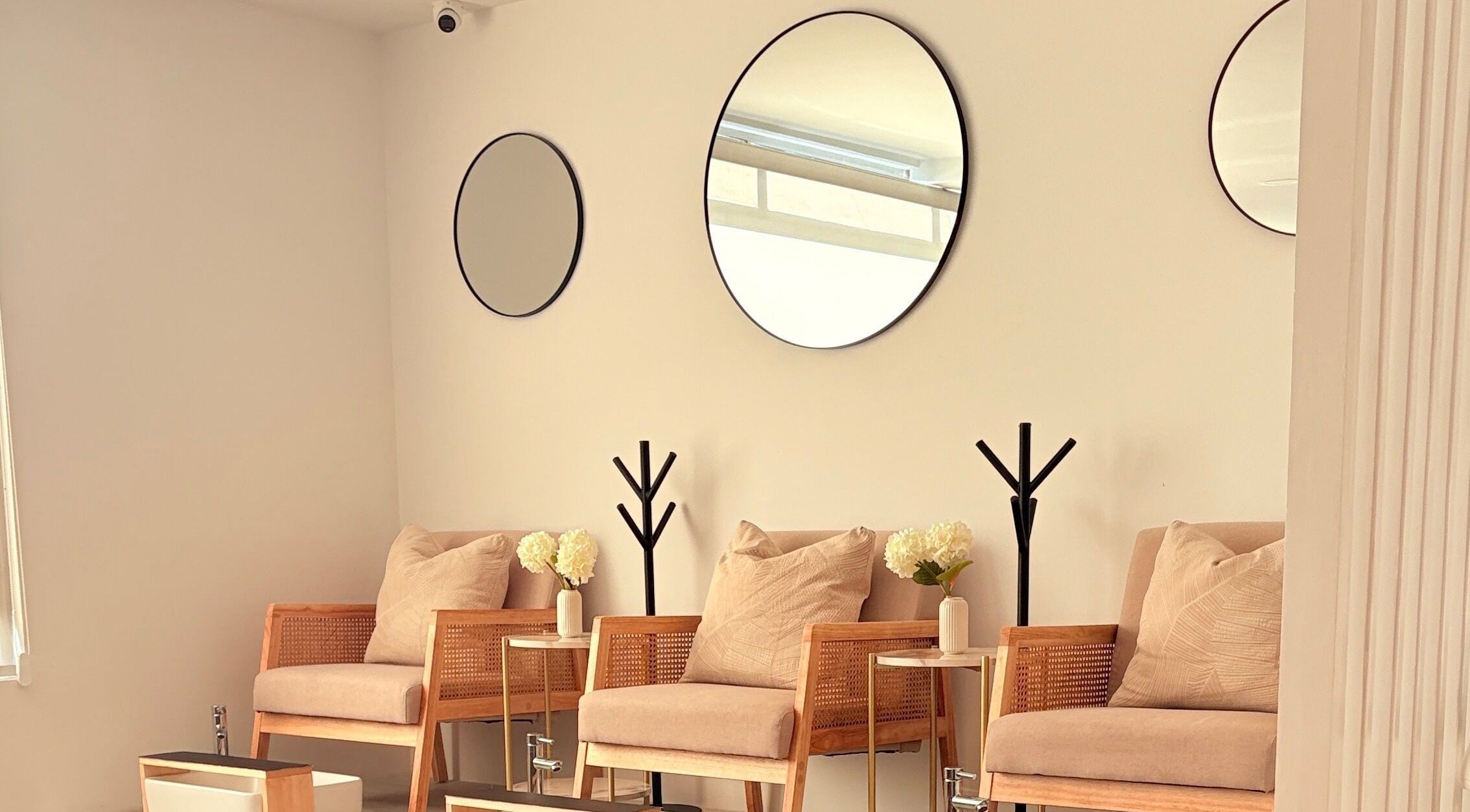 Área de espera elegante en Aura Nails Salón, Tijuana, Baja California, MX con sillas modernas y espejos minimalistas.